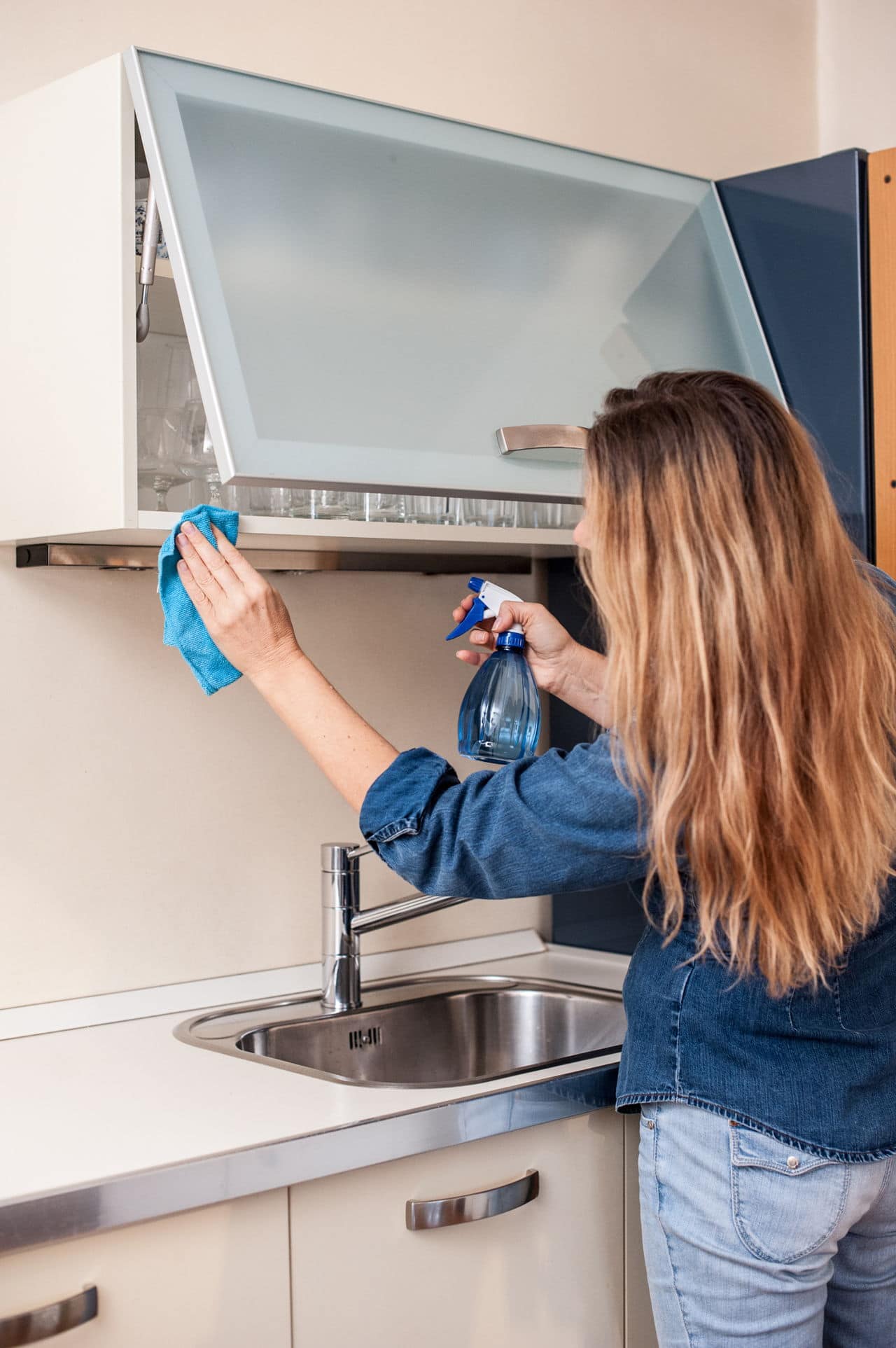 Woman-cleans-glass-kitchen-cabinet